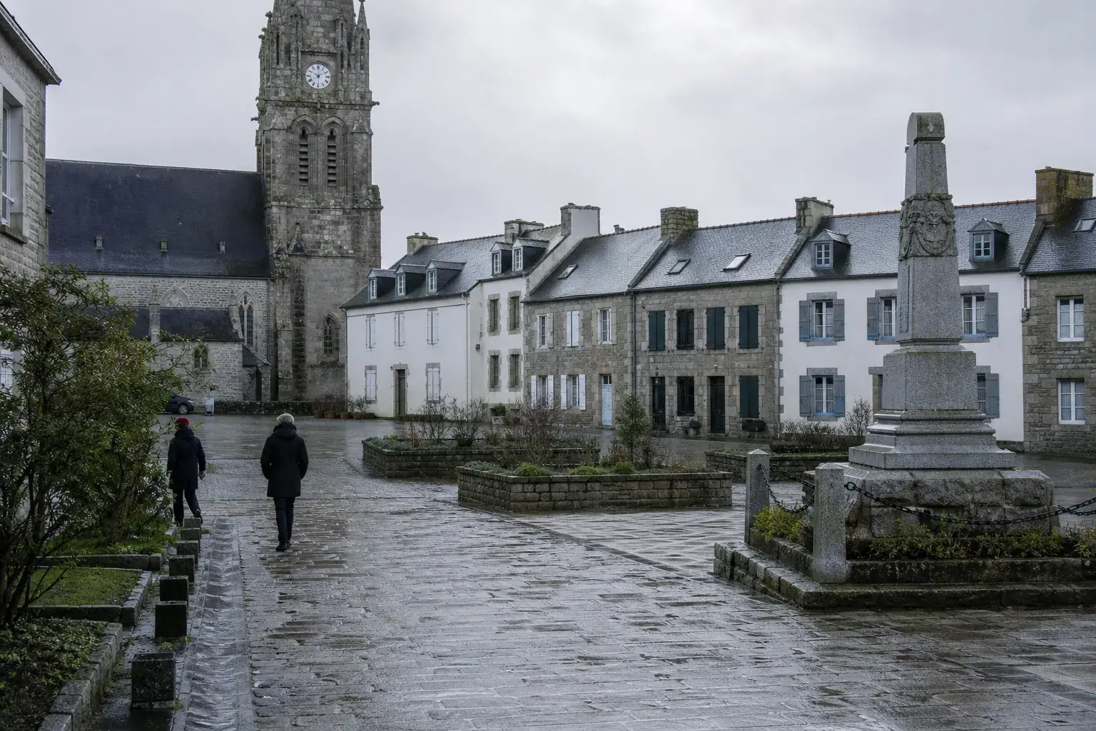 Centre d’un bourg breton : clocher de granit et maisons mitoyennes à toiture d’ardoise autour de la place