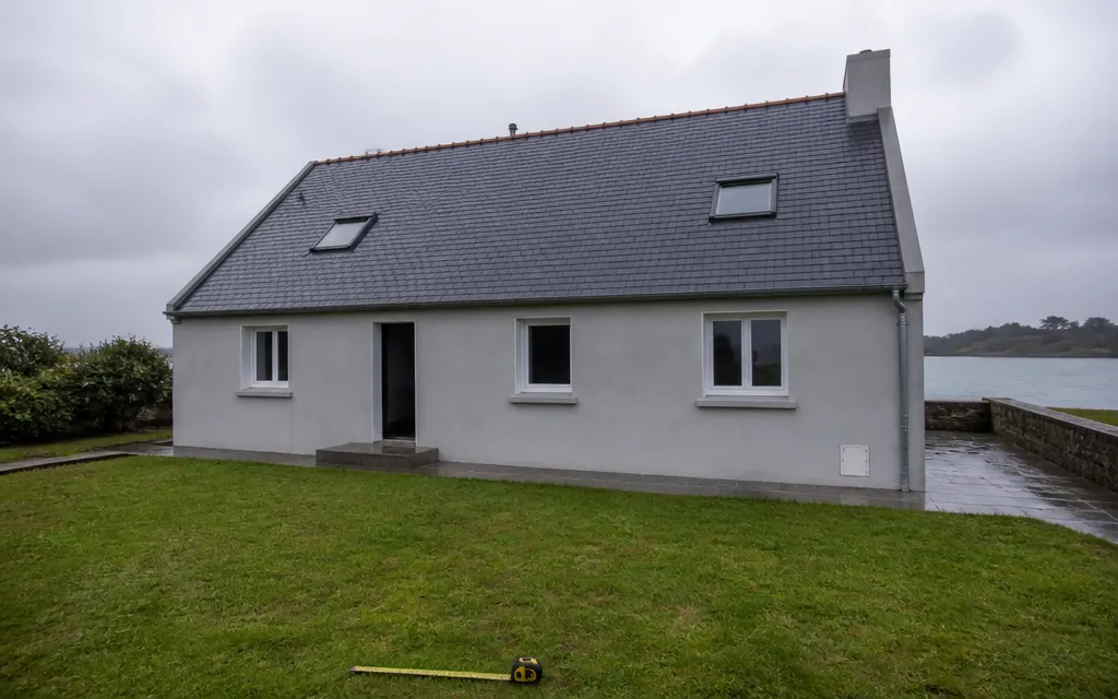 Maison individuelle vue entière depuis le jardin, toiture d’ardoise visible du faîtage à l’égout