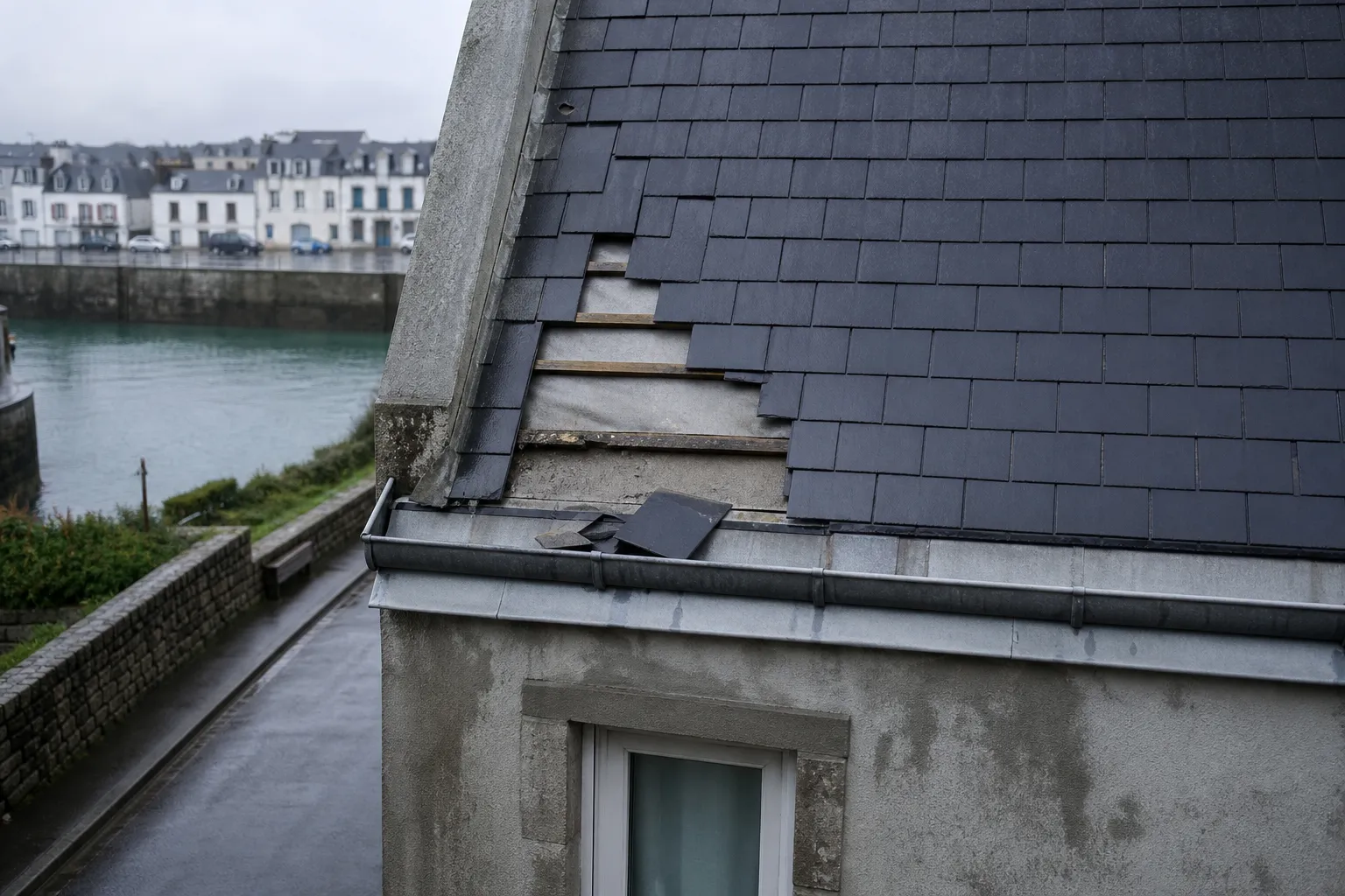 Ardoises manquantes près de la rive après un coup de vent, écran de sous-toiture apparent